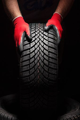 Gloved hands inspecting the tread of an upright tire