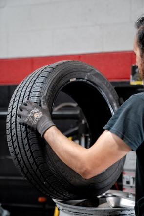 Technician handling a tire on workshop equipment